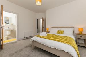 a bedroom with a large bed with a yellow blanket at Park View - 4 Star Luxury in Belfast