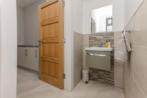 a bathroom with a sink and a wooden door at Park View - 4 Star Luxury in Belfast +21 photos