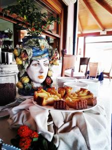 a table with a plate of pastries and a statue at Hotel Eros in Vulcano