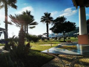 un parque con palmeras, mesa y sillas en Hotel Eros en Vulcano