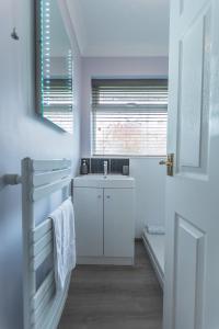 a white bathroom with a sink and a window at Kings Field Maisonette in Southampton