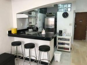 een keuken met 3 barkrukken en een aanrecht bij Ótimo Conjugado - Estúdio - Praia do Flamengo - RJ in Rio de Janeiro +15 foto's