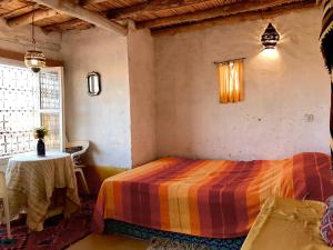 a bedroom with a bed in a room with a table at Auberge Chez Julia in Merzouga