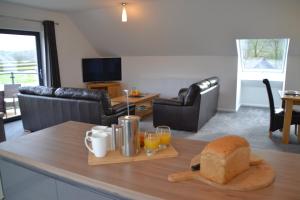 a living room with a table with bread and orange juice at Gerycastell Luxury Holiday Apartment with Stunning Views & EV Station Point in Carmarthen