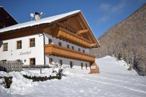 een gebouw met sneeuw op de grond naast een berg bij Lanerhof in Riva di Tures