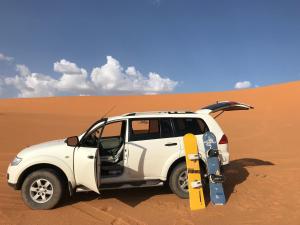 a white suv with skis parked in the desert at Auberge Chez Julia in Merzouga