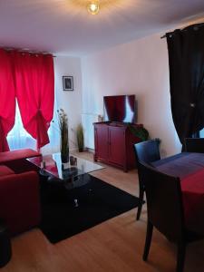 ein Wohnzimmer mit einem roten Sofa und einem Tisch in der Unterkunft Grand F3 CONFORTABLE 5 mn de Paris et proche Disneyland in Maisons-Alfort