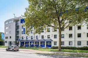 a white building with a car parked in front of it at ibis budget Karlsruhe in Karlsruhe