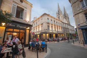 Une Chambre Chez Dupont في بوردو: مجموعة من الناس يجلسون على الطاولات في شارع المدينة