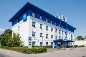 um grande edifício branco com um telhado azul em ibis budget Frankfurt Offenbach Süd em Offenbach