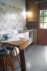 a kitchen with a sink and a table with stools at Mandala Chalés in Guarda do Embaú