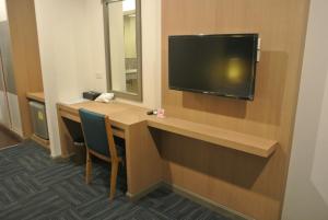 a hotel room with a desk with a television on a wall at S Tara Grand in Suratthani