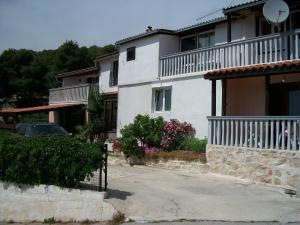a white house with a car parked in front of it at Apartments Luka in Tisno