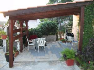 a wooden pergola with chairs and tables on a patio at Apartments Luka in Tisno