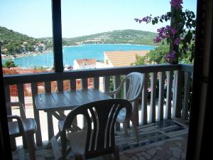 a table and chairs on a balcony with a view of the water at Apartments Luka in Tisno