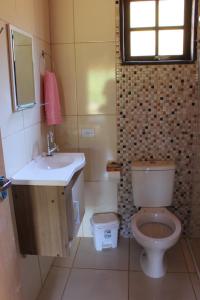 uma casa de banho com um WC, um lavatório e uma janela em Chalés Cachoeira Cafundó em Bueno Brandão