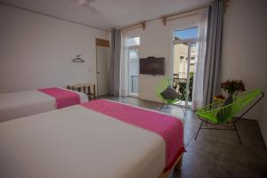 a hotel room with two beds and a balcony at Hotel Mamá Carlota in Querétaro