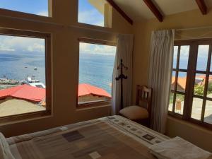 a bedroom with a bed and two large windows at JACHA INTI in Isla de Sol