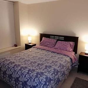 a bedroom with a bed with a purple bedspread and two lamps at Laguna Bahia Algarrobo in Algarrobo