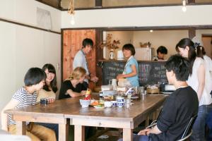 un grupo de personas sentadas alrededor de una mesa en un restaurante en 1166 Backpackers, en Nagano