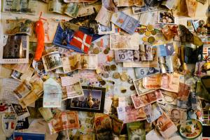 a wall covered in lots of different currencies at 1166 Backpackers in Nagano