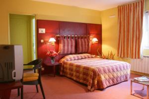 una camera d'albergo con letto, tavolo e TV di Les Colonnes Strasbourg Zenith a Strasburgo