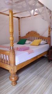 1 dormitorio con cama de madera y dosel en Sasagara Beach Villa, en Tangalle