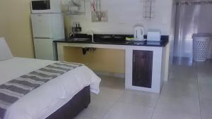 ein Schlafzimmer mit einem Bett und eine Küche mit einem Waschbecken in der Unterkunft Country Rose in Hluhluwe