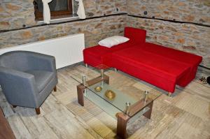 a living room with a red couch and a chair at Traditional Stone Villa "To Petrino" in Florina