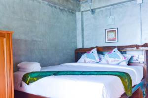 a bedroom with a bed with white sheets and pillows at Baan Tubkaek Hotel in Tab Kaek Beach