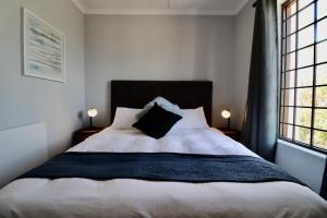 a bedroom with a large white bed with two lamps at Carole's Cottage in Hermanus