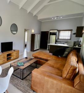 a living room with a brown couch and a table at Carole's Cottage in Hermanus