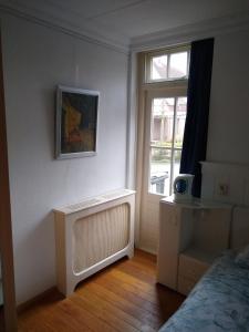 1 dormitorio con radiador, ventana y cama en Folmerhuis, en Oostkapelle