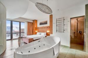 a bathroom with a tub and a bedroom with a bed at Radisson Blu Resort Bukovel in Bukovel