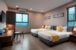 a hotel room with two beds and a desk at Golden Season Hotel in Ninh Binh