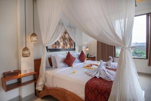 sypialnia z białym łóżkiem z baldachimem w obiekcie Mahadana Ubud w mieście Ubud