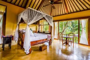 a bedroom with a canopy bed and a table at Villa Beji Indah in Ubud +58 photos