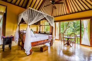 1 dormitorio con cama con dosel y mesa en Villa Beji Indah, en Ubud