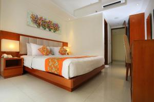 a bedroom with a large bed with an orange blanket at Bali Sun Tropical Hotel & Spa - formerly The Sun Hotel & Spa Legian in Legian +58 photos