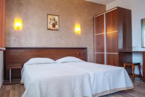 a bedroom with a white bed with a wooden headboard at Chrystal Guest House in Obzor