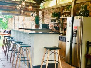 a kitchen with a counter with stools and a refrigerator at Ylang Garden Villa in Hoi An