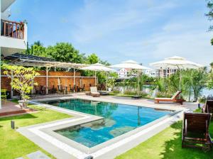 a swimming pool in a yard with chairs and umbrellas at Ylang Garden Villa in Hoi An
