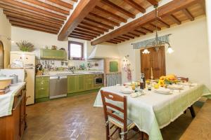 ラディコーファニにあるVilla Podere Olivetoのテーブル付きのキッチン、緑のキャビネット付きのキッチン