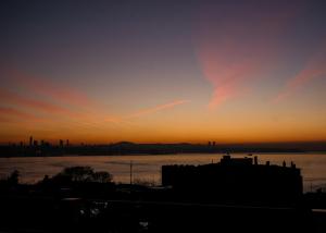 een zonsondergang boven een lichaam van water met een stad bij Ligos in Istanbul