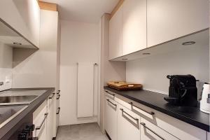 韋爾比耶的住宿－Ambassador 003，厨房配有白色橱柜和黑色台面