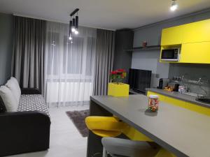 a kitchen with yellow cabinets and a table with yellow chairs at Travel Homzzz Central Apartments - Piata Trandafirilor in Târgu-Mureş +16 photos