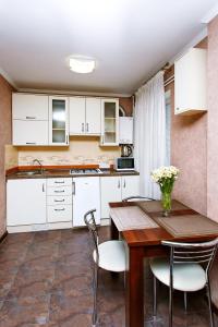 une cuisine avec des placards blancs et une table et des chaises en bois dans l'établissement Comfortable apartment in the center, à Tchernihiv