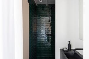 a green tiled shower in a bathroom with a sink at Het Witte Kasteel in Loon op Zand