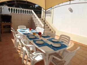 una mesa con sillas blancas y platos azules. en Apartamento Mariamar en Olhos de Água