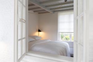 een witte slaapkamer met een bed en een raam bij Het Witte Kasteel in Loon op Zand